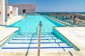 Et roolftop-infinity pool med frit udsyn til havet og bybilledet.
