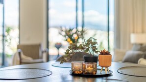 A modern living room with a large window, a coffee table, and decorative plants. - Inf26f - Modern and Bright City Apartment (Estepona)