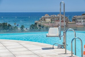 En swimmingpool med udsigt over havet og bygninger i baggrunden.