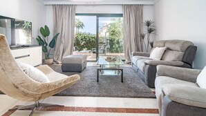 Una sala de estar moderna con un sofá, un sillón y una mesa de centro de vidrio.