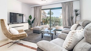 Una sala de estar moderna con un sofá, un sillón y un televisor de pantalla plana sobre un mueble blanco.