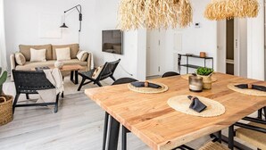 En moderne stue med et træbord, sorte stole, en beige sofa og en sort bænk.
