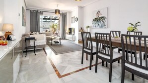 A modern living room with a dining area, featuring a sofa, coffee table, and a dining table with chairs. - Lcr4 - Large 3-bedroom Apartment Near Beach (Marbella)