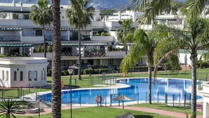 A resort with a swimming pool, palm trees, and a mountainous backdrop. - Lcr4 - Large 3-bedroom Apartment Near Beach (Marbella)