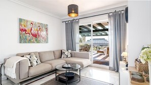 A modern living room with a beige sofa, a glass coffee table, and a painting of flamingos. - Lcr4 - Large 3-bedroom Apartment Near Beach (Marbella)