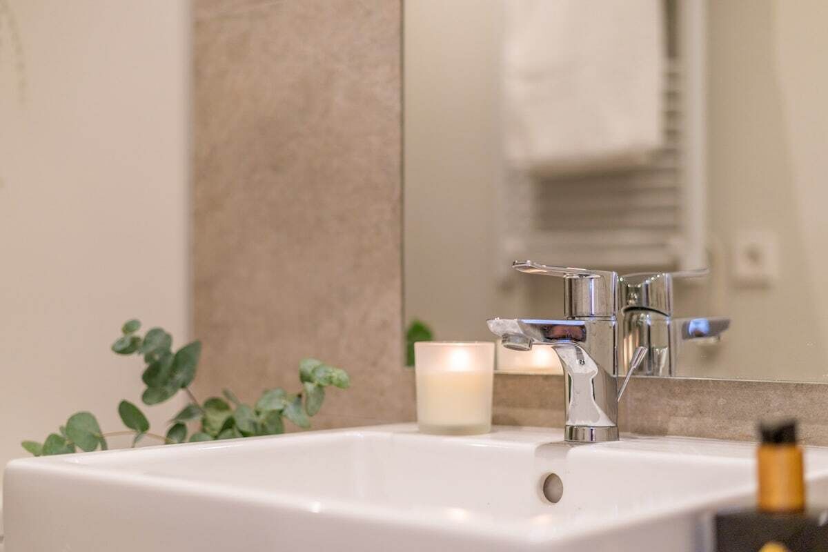 A bathroom sink with a mirror, a faucet, and a candle.