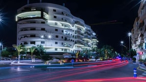 Un hôtel à plusieurs étages doté de balcons, d’une façade incurvée et de fenêtres illuminées.