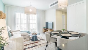 Un salon moderne comprenant un canapé, une table basse, un téléviseur et un coin repas avec des chaises et une table.