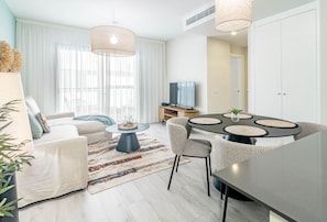 En moderne stue med sofa, sofabord, fjernsyn og spiseplads med stole og bord.