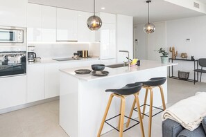 A modern kitchen with white cabinetry, a central island with stools, and pendant lighting. - Lme103a - Bright Modern Flat With Amazing Terrace (Estepona)
