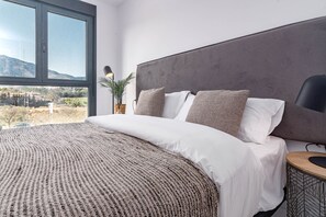 Un dormitorio moderno con una cama grande, vistas al exterior y un diseño minimalista.