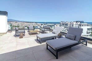 A rooftop terrace with outdoor seating, a view of the city, and a clear sky. - Lme103a - Bright Modern Flat With Amazing Terrace (Estepona)