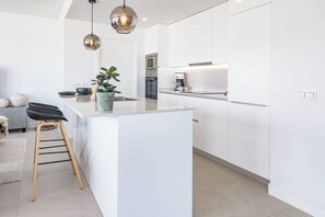 A modern kitchen with white cabinetry, a central island, pendant lighting, and a small seating area with a stool. - Lme103a - Bright Modern Flat With Amazing Terrace (Estepona)