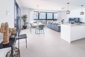 Un apartamento moderno con comedor, cocina y sala de estar, que cuenta con ventanas amplias y vista a la ciudad.