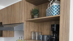 Eine Küche mit Holzausstattung, einer eingebauten Ablagefläche mit Pflanze, einer Kaffeemaschine und einem Glaskeramikkochfeld.