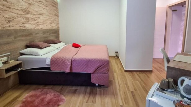 Une chambre moderne avec un lit, une table de chevet et un petit bureau équipé d’une bouilloire.