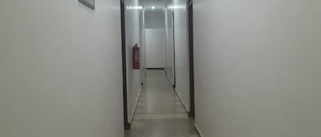 A long, narrow hallway with white walls and a tiled floor.