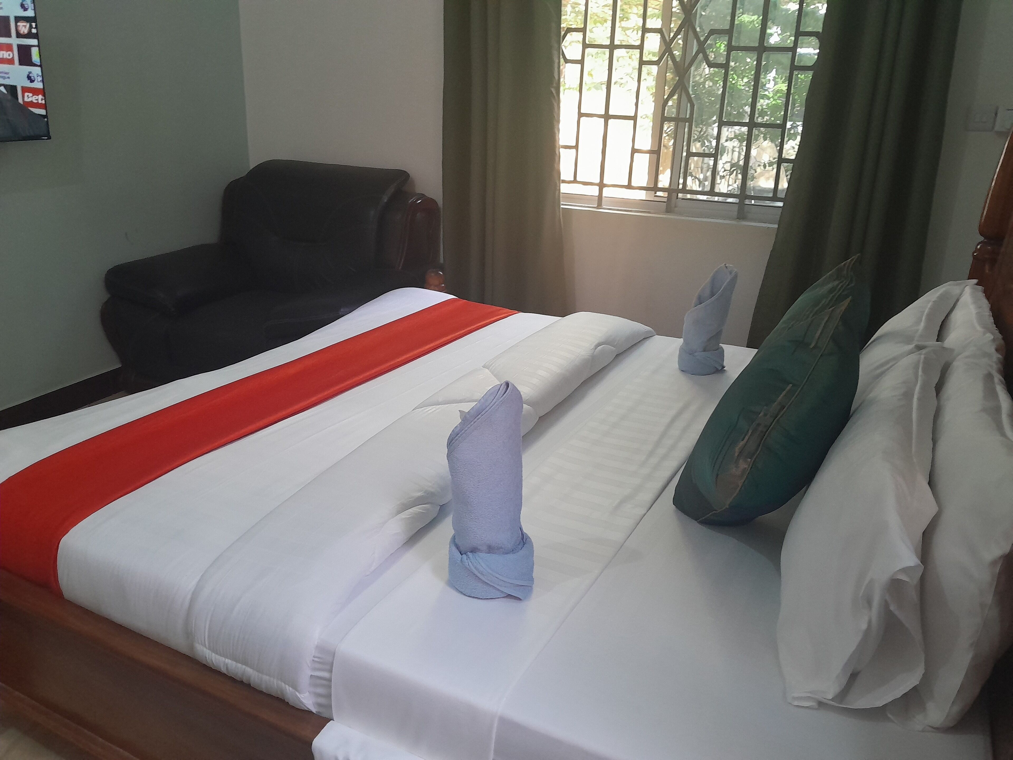 Habitació d'hotel amb llit, una cadira i finestra amb cortines.