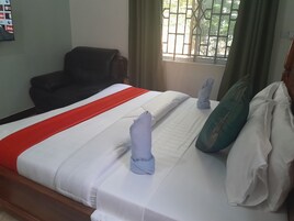Una habitación de hotel con una cama, una silla y un ventanal con cortinas.
