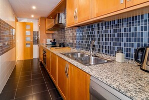 Une cuisine moderne avec des meubles en bois, des plans de travail en granit, un évier double et un pare-feu en carrelage.