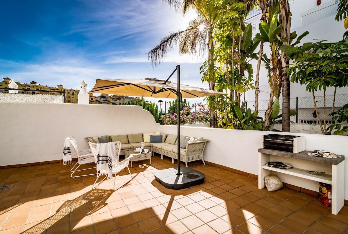 A patio with outdoor furniture, a table, and a grill.