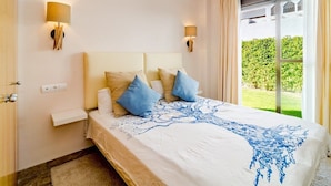 A bedroom with a bed, two wall-mounted lamps, a window with curtains, and a view of greenery outside. - Gh-modern 2 bed Apartment With Pool in Estepona (Estepona)