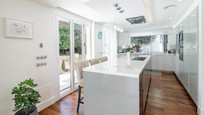 A modern kitchen with a large island, wooden flooring, and a view of the outdoors. - Villa Nottingham Stunning Private Villa (Marbella)
