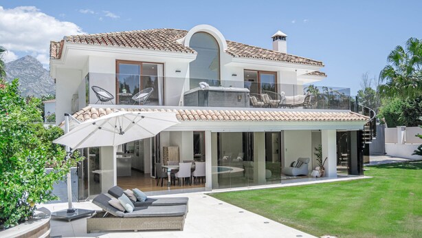 A modern two-story house with a covered patio, outdoor seating, and a view of mountains. - Villa Nottingham Stunning Private Villa (Marbella)