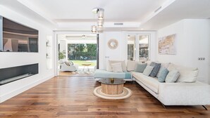 A modern living room with a sectional sofa, a flat-screen TV, and a round coffee table. - Villa Nottingham Stunning Private Villa (Marbella)