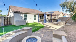 Una propiedad residencial con un patio, una fogata y una zona de estar exterior techada.