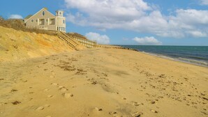 Ein Strand mit einem Haus und einer Holzpromenade.