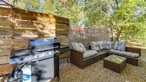 Un patio al aire libre con una parrilla, muebles de mimbre y una valla de madera.