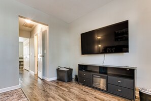 Una sala de estar moderna con un televisor de pantalla plana montado en la pared, un mueble de madera oscura y una alfombra estampada en el suelo.