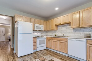 Una cocina moderna con armarios de madera, un refrigerador blanco, un microondas, una estufa y un lavavajillas.