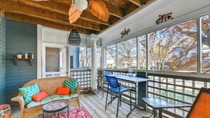 Une véranda avec un canapé en osier, des chaises bleues et une table.