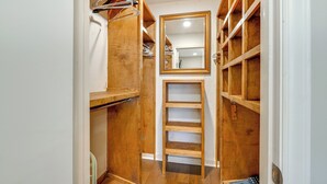 Un dressing avec des étagères en bois, un miroir et une tringle pour suspendre les vêtements.