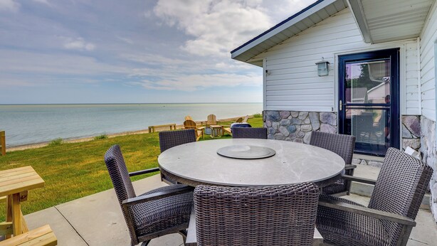 A patio with a round table and wicker chairs, overlooking a body of water. - Waterfront Lake Huron Getaway w/ Private Beach (Port Hope)