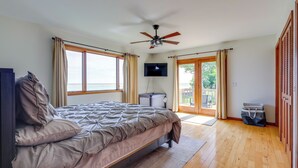 A bedroom with a bed, a ceiling fan, a TV, and a view through a glass door to the outside. - Waterfront Lake Huron Getaway w/ Private Beach (Port Hope)