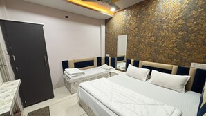 Quarto de hotel com uma cama grande, uma cama menor, uma escrivaninha e um guarda-roupa.