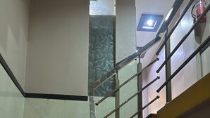 Escadaria com corrimãos e guarda-corpo de metal, levando a um patamar com uma pequena janela.