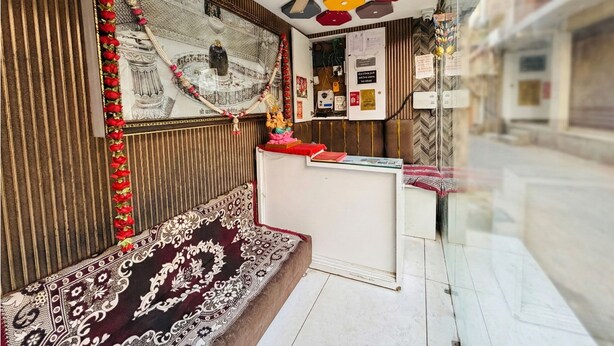 Um quarto com carpete estampado, um banco de madeira, uma parede decorativa com guirlanda floral e um teto com luminárias hexagonais.