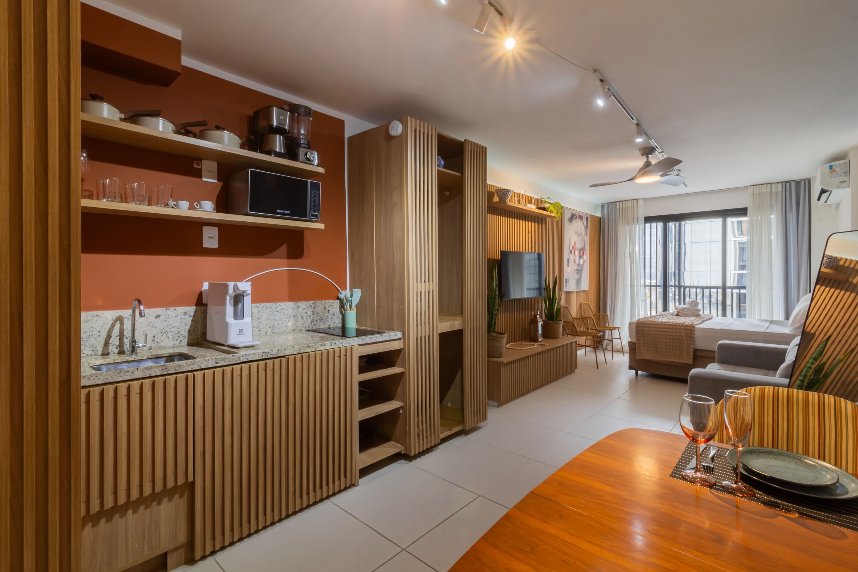 A modern kitchen with wooden cabinetry, a built-in microwave, and a coffee maker.