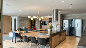 A modern kitchen with a central island, built-in appliances, and a dining area with a sofa and chairs. - 11 Minutes From the Museum of Tomorrow Vi19 (Rio de Janeiro)