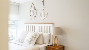 Een slaapkamer met een bed, kussens, een nachtkastje met een lamp en decoratieve wandpanelen.