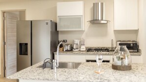 Een moderne keuken met een roestvrijstalen koelkast, een inbouwoven, een magnetron en een gasfornuis.
