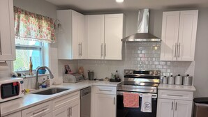 A modern kitchen with white cabinets, stainless steel appliances, and a wooden floor. - Dragonfly Cove + Hot Tub • Fire Pit • Lake Views • Sleeps 10 (Estill Springs)