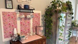 A cozy coffee bar area with a floral wallpaper, a coffee machine, and a vintage cabinet with plants. - Dragonfly Cove + Hot Tub • Fire Pit • Lake Views • Sleeps 10 (Estill Springs)