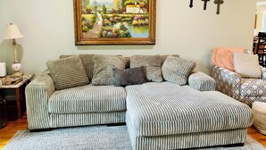 A living room with a sectional sofa, a painting of a landscape, and three wall-mounted crosses. - Dragonfly Cove + Hot Tub • Fire Pit • Lake Views • Sleeps 10 (Estill Springs)