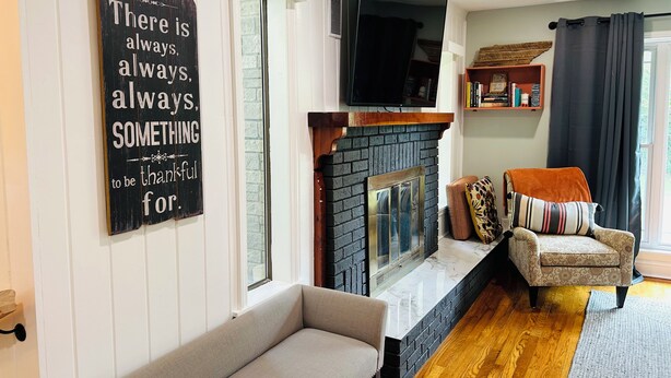 A living room with a fireplace, a sofa, a television, and a motivational quote on the wall. - Dragonfly Cove + Hot Tub • Fire Pit • Lake Views • Sleeps 10 (Estill Springs)