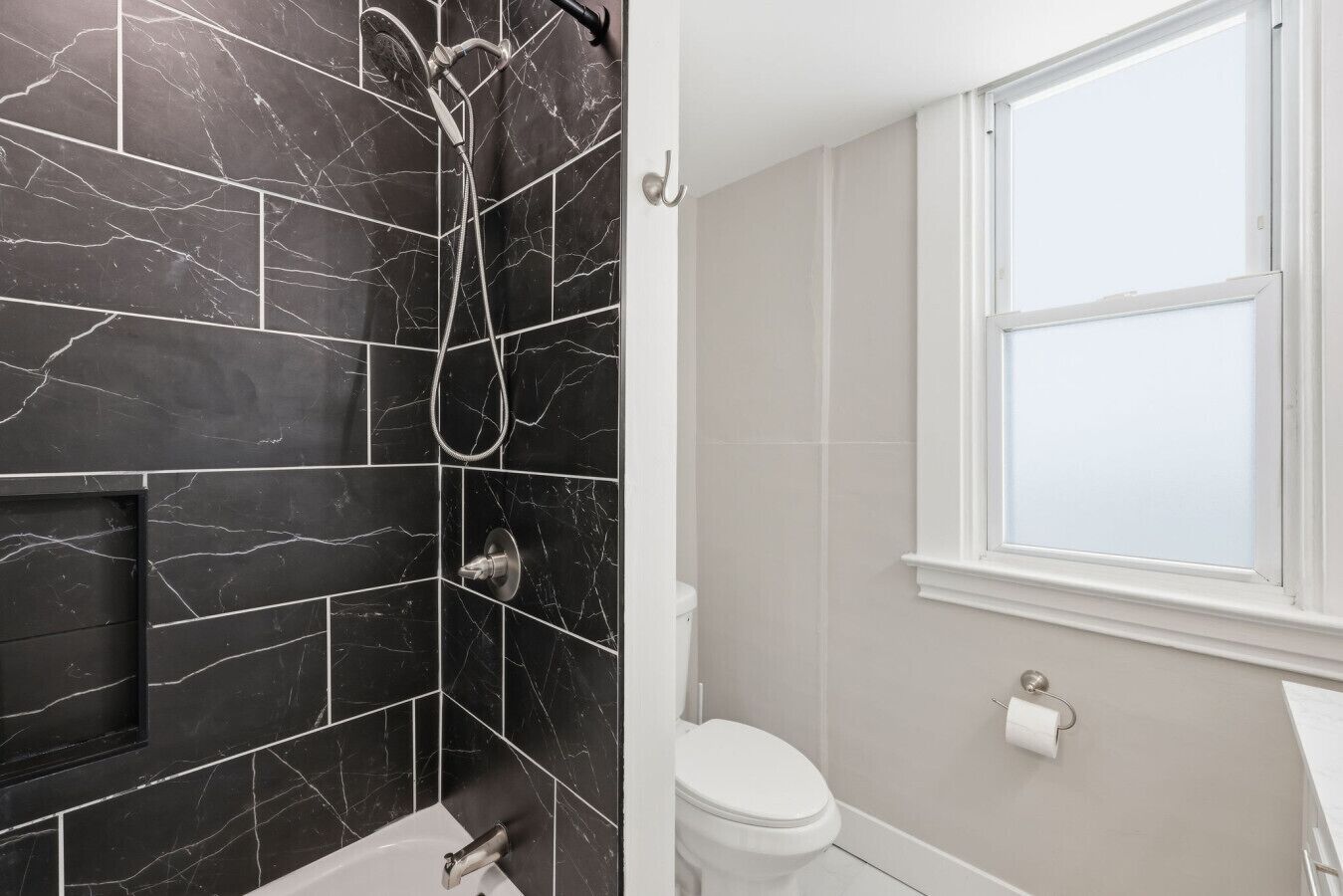 Un baño con ducha, inodoro y ventana.